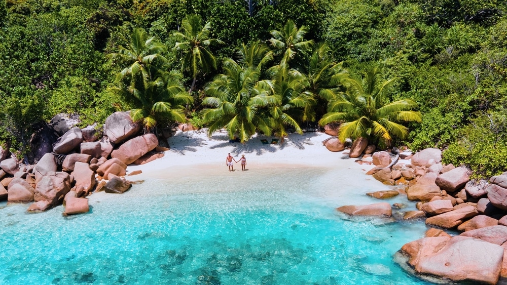 Een prachtig uitzicht vanuit de lucht vangt een paar dat geniet van een vakantie in Anse Lazio op Praslin Island, Seychellen. De turquoise lagune en weelderige palmbomen creëren een tropisch paradijs.