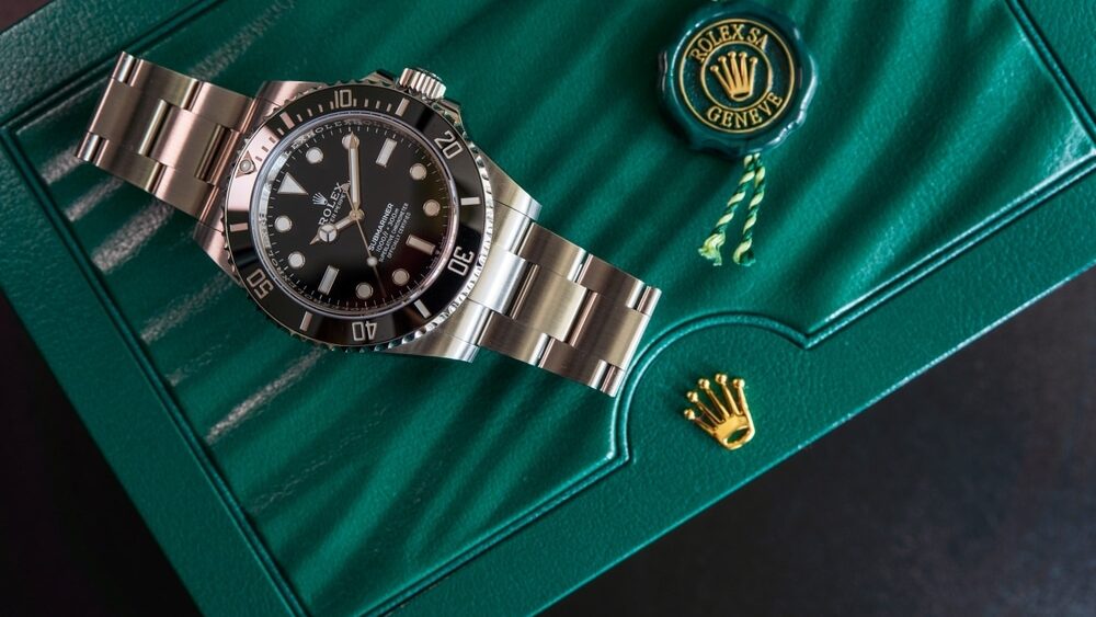 Rolex polshorloge keramische bezel model zwarte oester eeuwigdurende onderzeeër geen datum 124060 is op zwarte plank met achtergrond van Rolex groene doos kroon logo