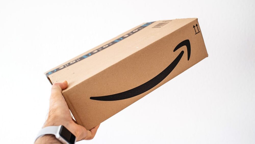 Man holding against white background Amazon Prime cardboard - showing the fast delivery box 