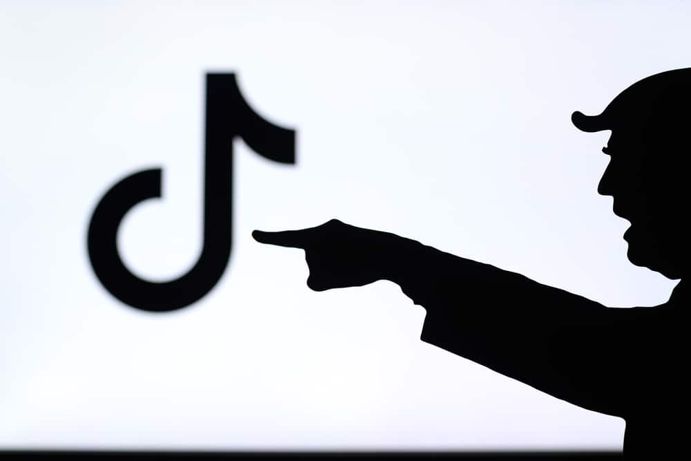 Donald Trump versus Tik Tok. Silhouette of American President in conflict with Chinese social network TikTok. Logo of company on screen in background. China vs USA.